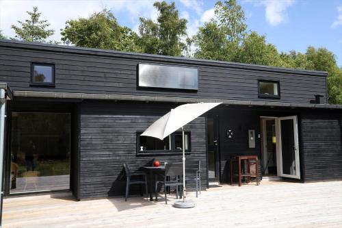 a black house with a table and chairs on a deck at 13370-Hojby-Havsbjergvej-11-A in Højby