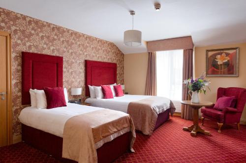 a hotel room with two beds and a chair at Kettles Country House Hotel in Swords