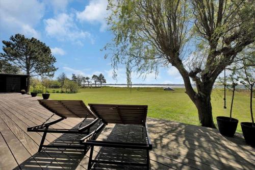 three chairs sitting on a deck near a tree at 18007-Holbaek-Fjorddalsvej-27 in Holbæk