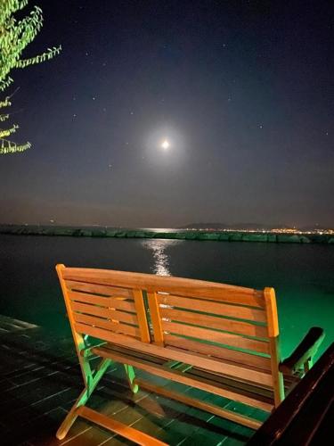 a wooden bench sitting on a dock near the water at night at Ayvalik Seafront Villa Mansion Summer House in Ayvalik in Ayvalık