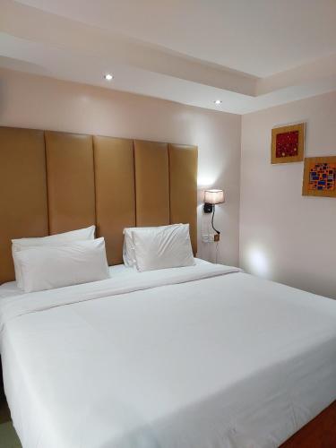 a bedroom with a large white bed with a headboard at Golden Tulip Hotel Port Harcourt -GTPH in Port Harcourt