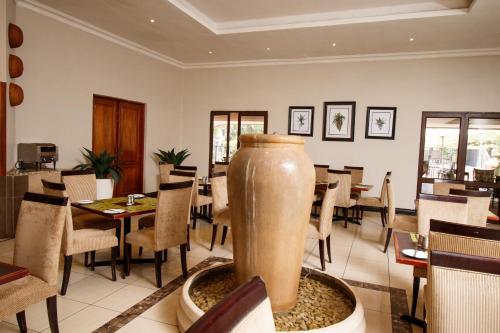 a restaurant with tables and chairs and a large vase at Royal Solwezi Hotel in Solwezi