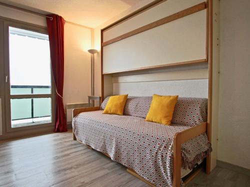 una camera da letto con un divano con cuscini gialli di Studio rénové 2018 avec parking couvert et animaux admis - FR-1-340-128 a Chamrousse
