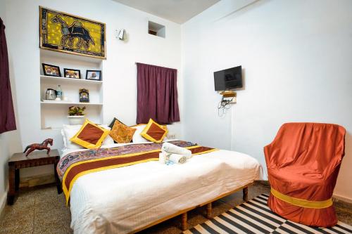 a bedroom with a bed and a chair in it at Hotel The Surya Jaisalmer in Jaisalmer