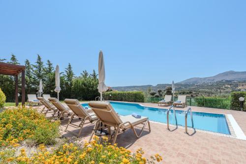 a villa with a swimming pool and chairs at Harmony villa in Rethymno Town