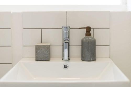 a sink with a bottle and a soap dispenser on it at Chic apartment with a beautiful view in Cape Town