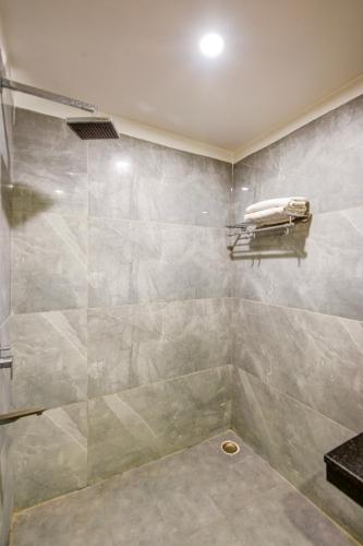 a bathroom with a shower with a glass door at Airport La Sapphire Hotel & Restaurant in New Delhi