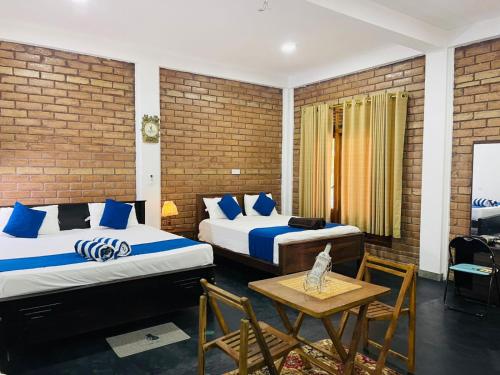 two beds in a room with a table and chairs at Sigiri Bawana in Sigiriya