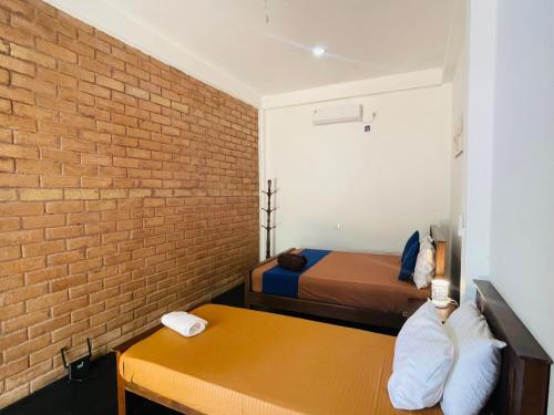 a room with two beds and a brick wall at Sigiri Bawana in Sigiriya
