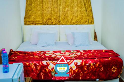 a bed with a red blanket and a yellow curtain at Aska Inn Hotel in Yendi