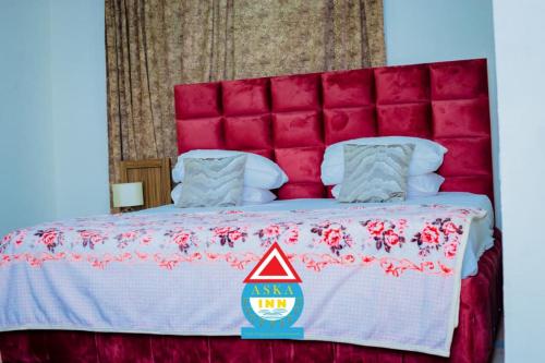 a large bed with a pink headboard with a red head board at Aska Inn Hotel in Yendi
