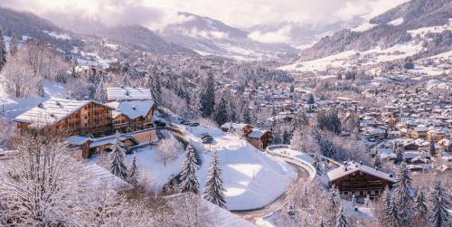 a village covered in snow with mountains in the background at Hôtel L'Arboisie in Megève