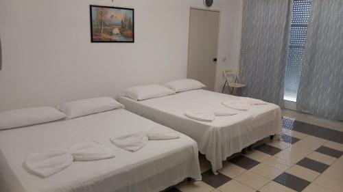 two beds in a room with white walls and tile floors at Antica Puglia 3 in Alberobello