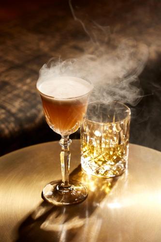 a drink and a glass of smoke on a table at Hôtel L'Arboisie in Megève