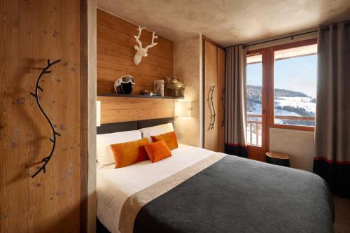 a hotel room with a bed and a window at Hôtel L'Arboisie in Megève
