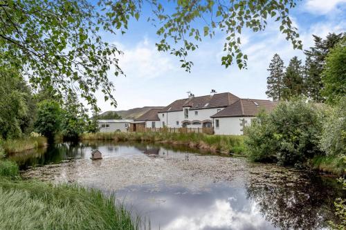 a river with houses in the background and a pond at 1 Bed in Newtonmore oc-c32414 in Newtonmore