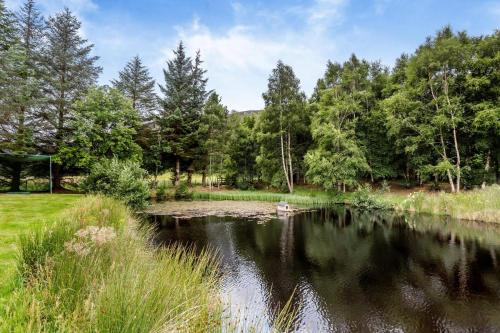 a pond in a park with a boat in the water at 1 Bed in Newtonmore oc-c32414 in Newtonmore