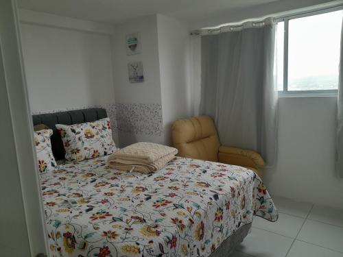 a bedroom with a bed with a comforter and a chair at Caruaru com Melhor Custo-Benefício in Caruaru
