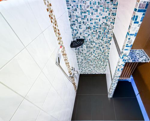 a bathroom with a shower with blue and white tiles at EASY Lodges Berlin in Berlin