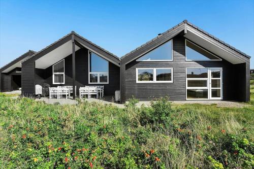 a black house with white windows and some bushes at FAN020-Fano-Hympelvej-16 in Fanø