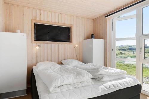 a bedroom with a bed with white sheets and a window at FAN020-Fano-Hympelvej-16 in Fanø