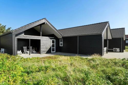 a black house with a black roof and a patio at FAN020-Fano-Hympelvej-16 in Fanø
