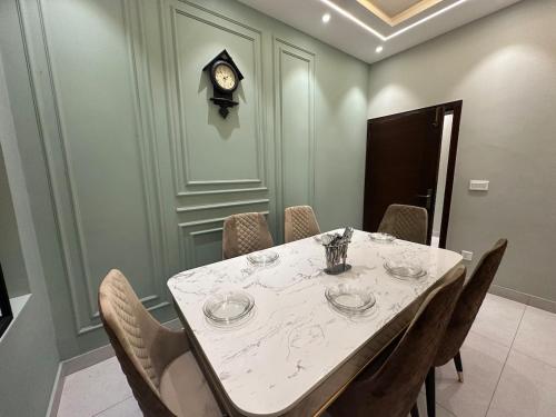 a dining room with a table with chairs and a clock at 2BR Modern Home in the heart of lahore New gardentown in Lahore