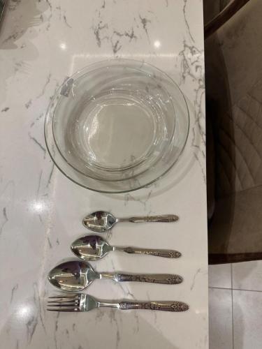 a group of silver spoons and a glass plate on a table at 2BR Modern Home in the heart of lahore New gardentown in Lahore