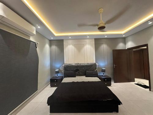a bedroom with a black bed and two night stands at 2BR Modern Home in the heart of lahore New gardentown in Lahore