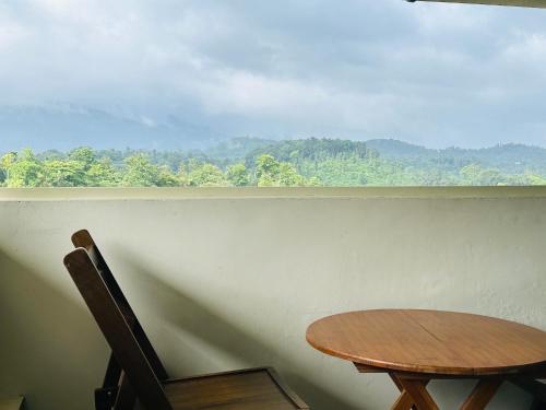 a table and a chair in front of a window at Western Ghats Holiday Home in Kalpetta