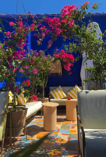 a patio with flowers and a couch and chairs at Casa Amina in Chefchaouene