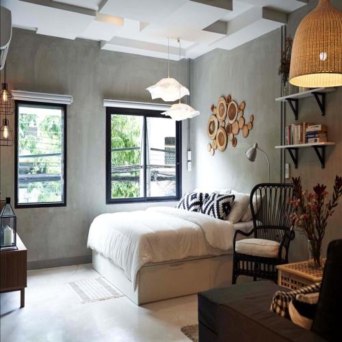a bedroom with a bed and a chair and windows at Collection O Jasaen Stylish Unique Hotel in Bangkok