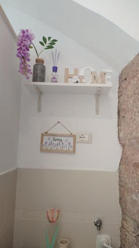 a bathroom with a shelf with flowers on the wall at Apartments Aurora Delle Rose in Assisi