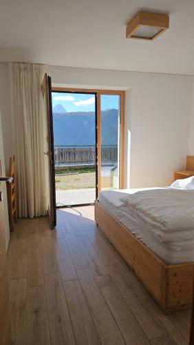a bedroom with a bed and a sliding glass door at Panorama Dolomiti in San Vigilio Di Marebbe