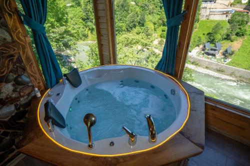 a bath tub with two faucets in front of a window at Cuneli bungalov in Çamlıhemşin