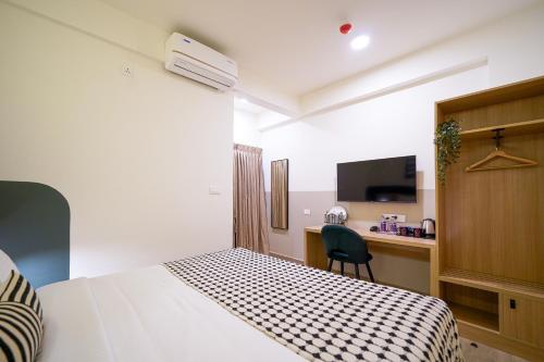 a bedroom with a bed and a desk with a television at Olive Hotel Hoodi by Embassy Group in Bengaluru