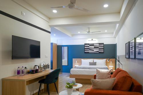 a bedroom with a bed and a desk with a couch at Olive Hotel Hoodi by Embassy Group in Bengaluru