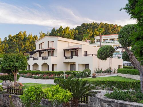 an exterior view of a building with a garden at Aegean Melathron Thalasso Spa Hotel in Kallithea Halkidikis