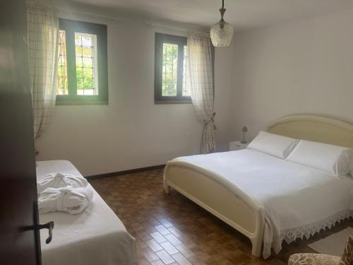 a white bedroom with two beds and two windows at Villa Rosa in Borso del Grappa