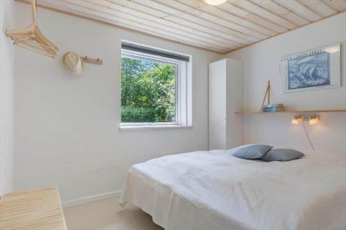 a white bedroom with a bed and a window at 8837-Glesborg-Enebaervej-30-A in Glesborg
