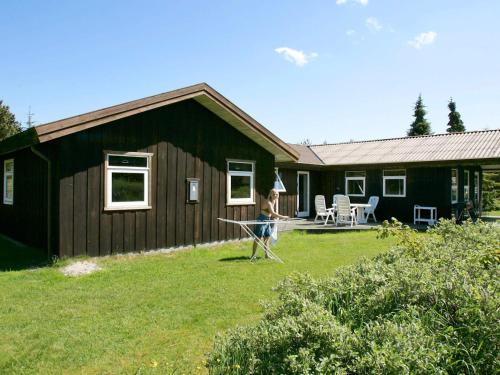 una mujer jugando con una cometa delante de una casa en 12 person holiday home in Pandrup-By Traum, en Rødhus
