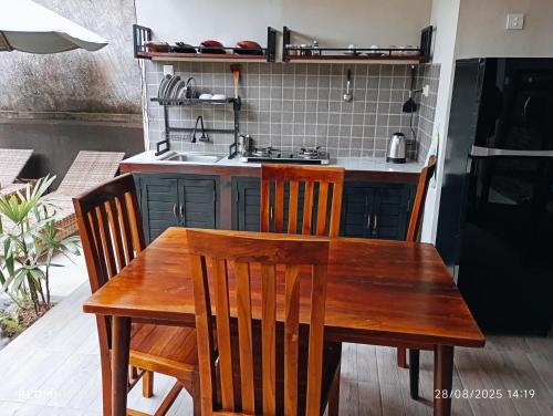 a kitchen with a wooden table and chairs and a stove at Bali Vanilli Villa in Sukawati