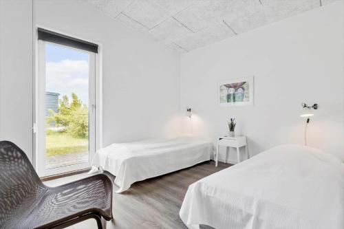 a white bedroom with two beds and a window at 8835-Glesborg-Skovsoen-50 in Glesborg