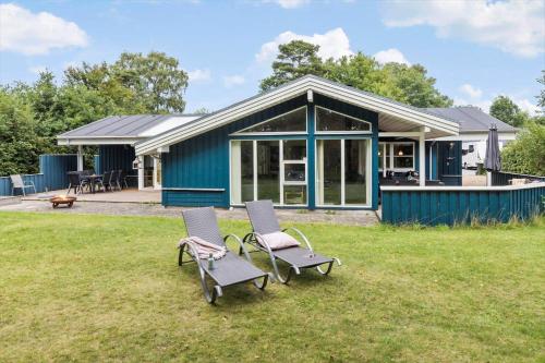 a blue house with two chairs in the grass at 8522-Grenaa-Nobilisvej-15 in Grenå