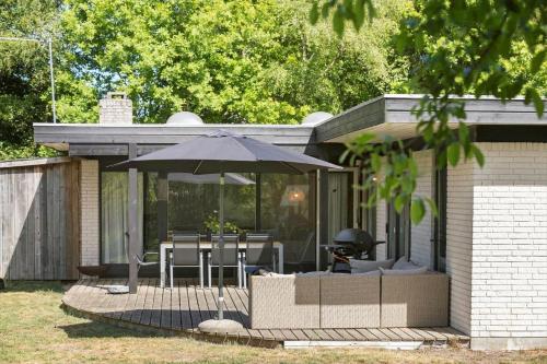 a patio with an umbrella and tables and chairs at 8915-Glesborg-Zachosvej-5 in Glesborg
