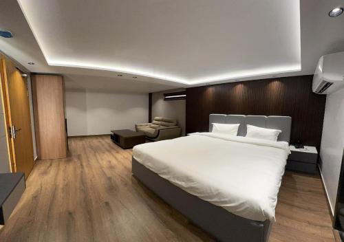 a bedroom with a large white bed and a chair at Plaza 14 in Jammu