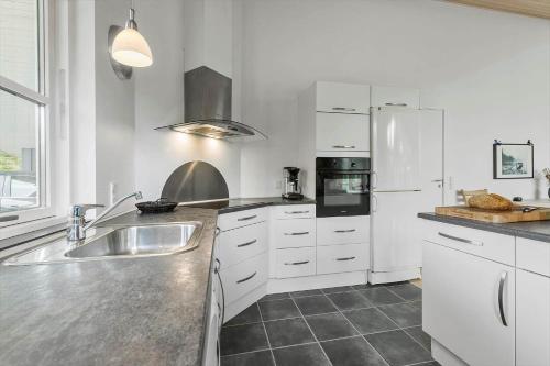 a white kitchen with a sink and a refrigerator at 8920-Orsted-Ternevej-16 in Ørsted