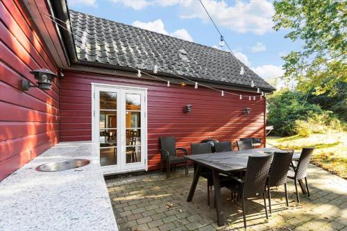 a patio with a table and chairs next to a red building at 8514-Grenaa-Sortebaervej-16 in Grenå