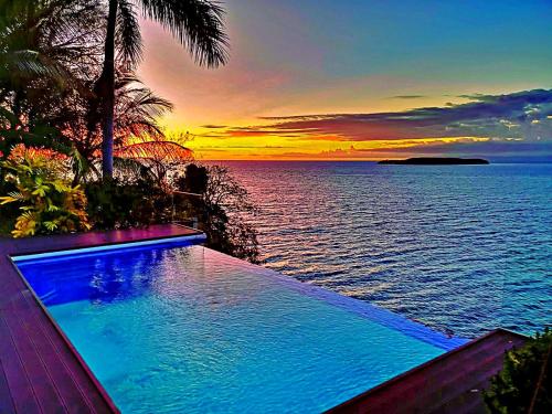 einen Pool mit Blick auf das Meer bei Sonnenuntergang in der Unterkunft Casa Acantilado Oslob - 3BR in Oslob