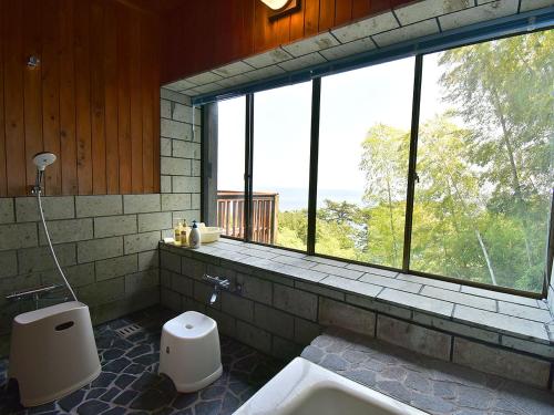 a bathroom with a tub and a toilet and a window at 伊豆稲取テラス-寛道- in Shimoda